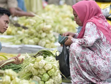 Pedagang melayani pembeli kulit ketupat untuk lebaran, Jakarta, Kamis (22/6). Menjelang Hari Raya Idul Fitri, pedagang kulit ketupat musiman mulai ramai di pasar tradisional. (Liputan6.com/Yoppy Renato)