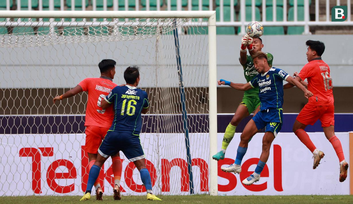 <p>Penjaga gawang Persib Bandung, Teja Paku Alam (tengah) berusaha menghalau bola dalam pertandingan lanjutan BRI Liga 1 2022/2023 melawan Borneo FC yang berlangsung di Stadion Pakansari, Bogor, Kamis (26/1/2023). (Bola.com/Ikhwan Yanuar)</p>