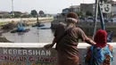 Warga menyaksikan proses pengerukan endapan tanah di aliran Sungai Ciliwung, Jakarta, Selasa (28/7/2020). Pengerukan endapan ini untuk memperlancar aliran air Sungai Ciliwung serta upaya pencegahan banjir saat musim hujan. (Liputan6.com/Helmi Fithriansyah)