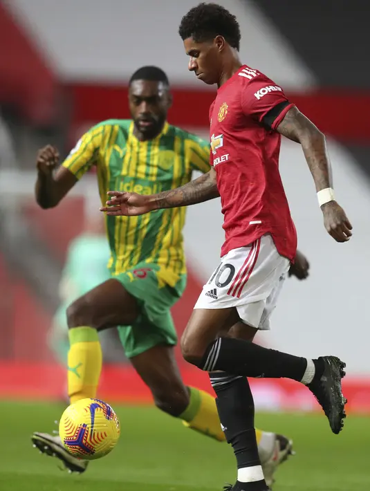 Penyerang Manchester United, Marcus Rashford mengontrol bola dari kawalan pemain Bromwich Albion, Semi Ajayi pada pertandingan Lanjutan Liga Inggris di stadion Old Trafford di Manchester, Inggris, Sabtu (21/11/2020). MU menang tipis atas West Bromwich Albion 1-0. (Cath Ivill/Pool via AP)