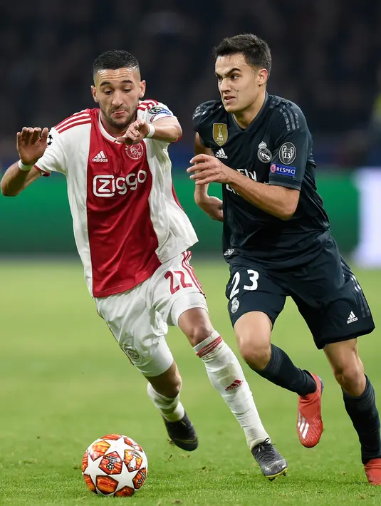 Gelandang Ajax, Hakim Ziyech berebut bola dengan bek Real Madrid, Sergio Reguilon pada leg pertama 16 besar Liga Champions di Johan Cruijff ArenA, Rabu (13/2). Real Madrid harus bersusah payah menaklukkan Ajax dengan skor tipis 2-1. (JOHN THYS / AFP)