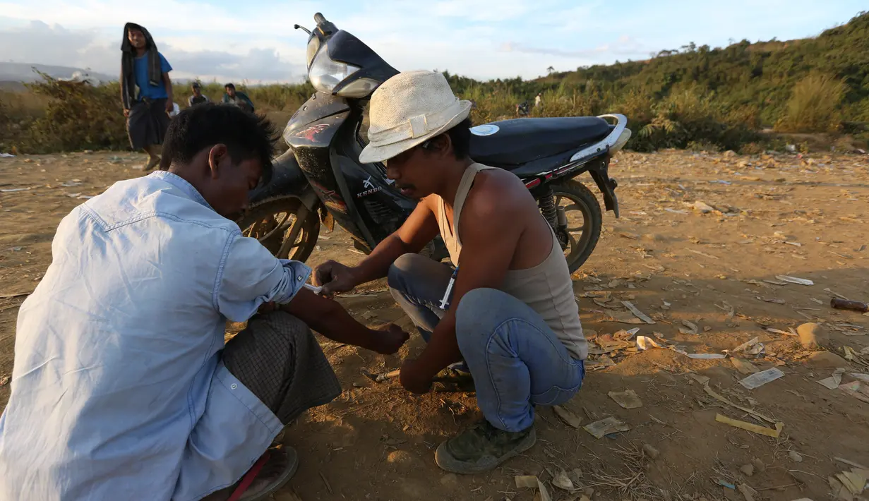 Seorang penambang membantu temannya menyuntikan heroin pada tubuhnya di Tambang batu giok di Hpakant, Myanmar, 29 November 2015. Kecanduan narkotika sudah merabak pada penambang batu giok. (REUTERS/Soe Zeya Tun)