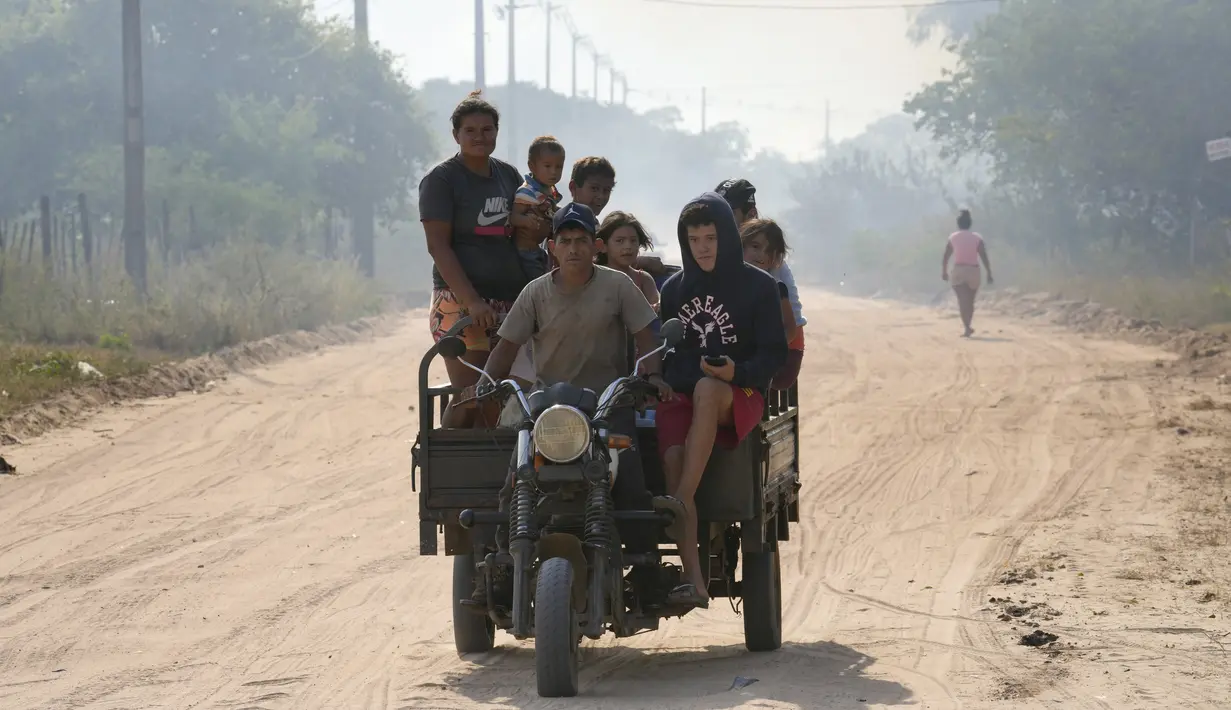 Sebuah sepeda motor membawa penduduk setempat yang telah dievakuasi dari rumah mereka selama kebakaran semak di lingkungan Banco San Miguel di Asuncion, Paraguay (18/1/2022). (AP Photo/Jorge Saenz)