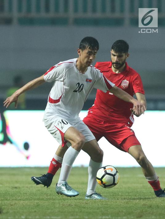 Pemain depan Korea Utara, So Jong Hyok (kiri) berebut bola dengan pemain Bahrain pada laga PSSI Anniversary Cup 2018 di Stadion Pakansari, Kab Bogor, Kamis (3/5). Laga dimenangkan Bahrain 4-1. (Liputan6.com/Helmi Fithriansyah)