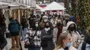 Pembeli mengenakan masker berjalan di sepanjang pasar Natal di taman Tuilerie di Paris, 20 Desember 2021. Negara-negara di Eropa mempertimbangkan pembatasan yang lebih ketat guna membendung gelombang baru infeksi COVID-19 yang didorong oleh varian omicron yang sangat menular. (AP Photo/Michel Euler)