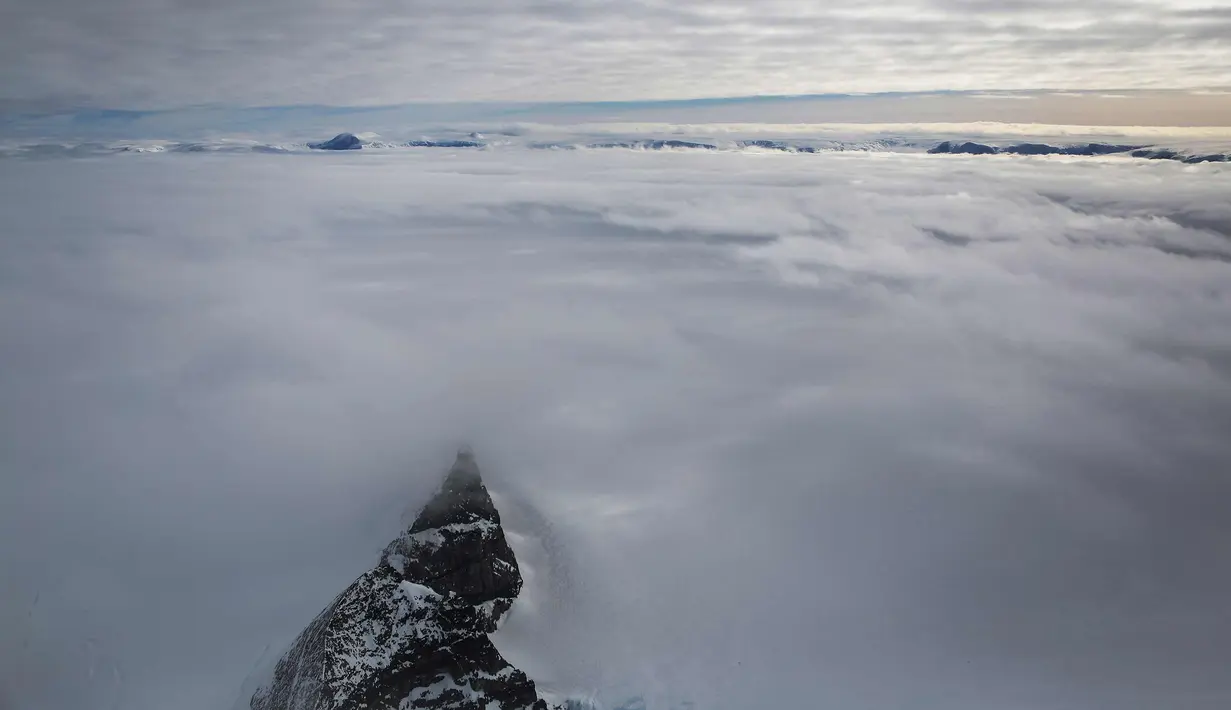 Puncak gunung dikelilingi laut es mengapung di lepas pantai Antartika (31/10). (Mario Tama/Getty Images/AFP)
