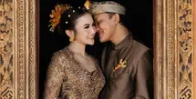 Sambil berpegang tangan mesra, Rizky Febian dan Mahalini tampil mengenakan busana adat Bali warna cokelat yang serasi. [@axioo]