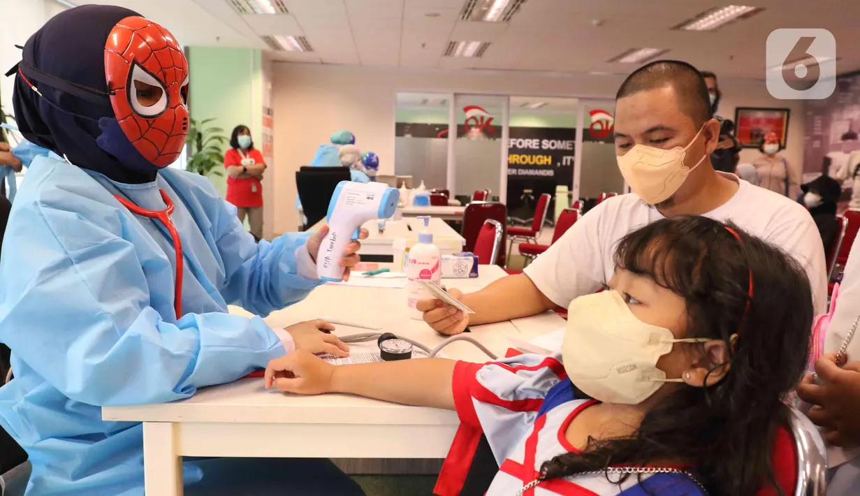 Petugas medis mengenakan topeng superhero mengecek kesehatan anak sebelum menyuntikkan vaksin Sinonvac kepada anak-anak saat mengikuti vaksinasi ke dua di Gedung  OJK, Jakarta, Minggu (16/01/2022). Sebanyak 350 anak karyawan OJK mengikuti vaksinasi Covid-19 dosis kedua. (Liputan6.com/Angga Yuniar)