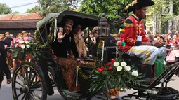 Presiden Jokowi dan Ibu Negara, Iriana berada di kereta kencana menuju Graha Saba Buana, Solo, Rabu (8/11). Pernikahan putri presiden Jokowi, Kahiyang Ayu dengan Bobby Nasution diiringi prosesi kirab kereta kencana. (Liputan6.com/Angga Yuniar)