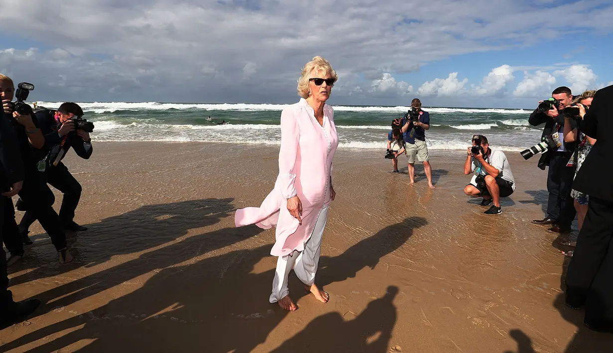 Duchess of Cornwall Camilla berjalan tanpa alas kaki di atas pasir pantai saat mengunjungi Broadbeach di Gold Coast, Kamis (5/4). Pangeran Charles dan Camilia ke Australia untuk menghadiri upacara pembukaan Commonwealth Games. (Mark Metcalfe/POOL/AFP)