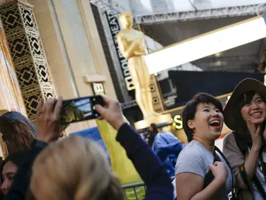 Wisatawan dari Jepang berselfie dengan latar belakang patung Oscar 2016 di luar Teater Dolby, Hollywood, California, Sabtu (27/2). Acara penghargaan Academy Awards ke-88 ini akan berlangsung pada Minggu (28/2) waktu setempat. (REUTERS/Adrees Latif)