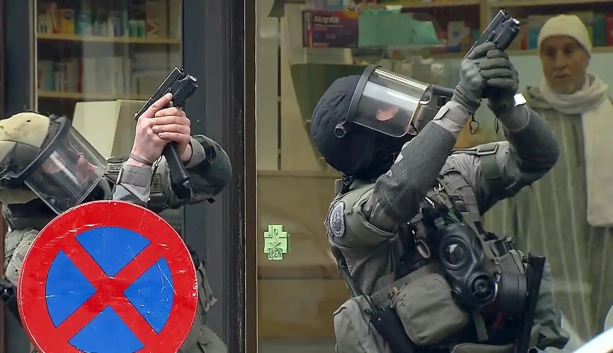 Dua Polisi antiteror Belgia bersenjata saat menggerebek sebuah apartemen di Molenbeek, Brussel, Belgia, (8/3). Wilayah ini memang dihuni oleh imigran-imigran asal Afrika Utara. (REUTERS/VTM)