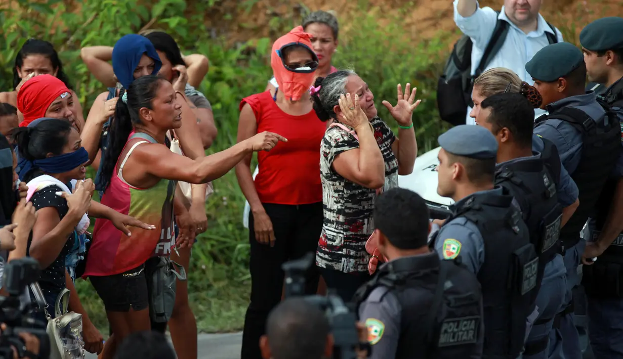 Kerabat dari narapidana bereaksi di hadapan polisi anti huru hara yang berjaga di pos pemeriksaan menyusul kerusuhan yang terjadi di dalam penjara kota Amazon, Brasil, Senin (2/1). Banyak korban yang tewas dalam keadaan terpenggal (REUTERS/Michael Dantas)