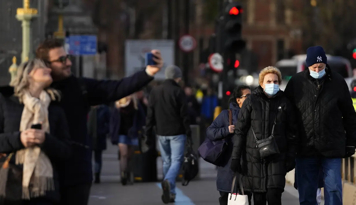 Orang-orang berjalan melintasi Jembatan Westminster di London, Kamis (9/12/2021). Perdana Menteri Inggris Boris Johnson kembali mendesak orang untuk bekerja dari rumah dan kewajiban menunjukkan sertifikat vaksin untuk memasuki klub malam dan tempat dengan kerumunan besar. (AP Photo/Frank Augstein)