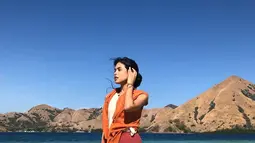 Tak melulu berada pegunungan dan hutan, Maudy juga tampak santai dan memesona saat bersantai di pantai. Outfitnya yang didominasi oranye ini membuat fotonya semakin estetik. (Liputan6.com/IG/@maudyayunda)