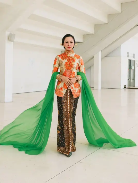 <p>Menyanyikan lagu Kebaya bersama 5 Wanita, Andien Aisyah kenakan kebaya Janggan bermotif bunga warna oranye. Dipadukan dengan kain Batik cokelat dan selendang berwarna hijau. Rambutnya pun ditata bergaya sanggul tekuk dengan tusuk konde di bagian samping. [@andienaisyah].</p>
