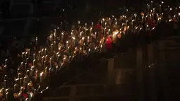 Orang-orang memegang obor saat demonstrasi untuk Ukraina yang diselenggarakan oleh Greenpeace di Heroes Square, Budapest, Hungaria, 9 Maret 2022. Invasi Rusia ke Ukraina telah memicu migrasi massal terbesar di Eropa dalam beberapa dekade. (AP Photo/Anna Szilagyi)