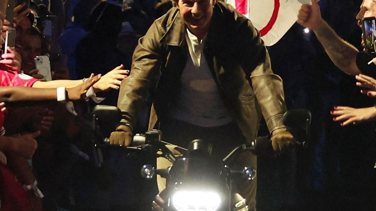 Tom Cruise juga bahkan menunggangi motor, mirip dengan adegan dalam film yang pernah dibintanginya, sambil membawa bendera Olimpiade. Foto: Reuters