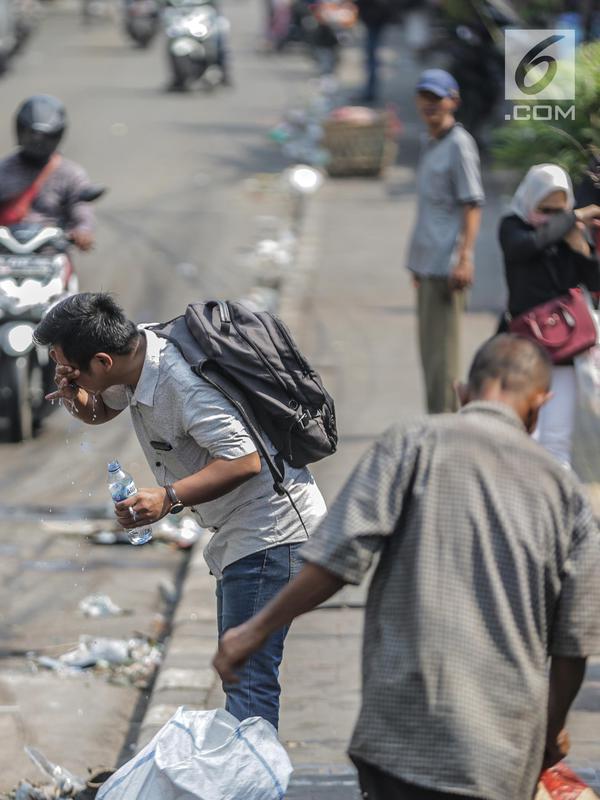 Seorang pria mencuci muka dengan air untuk menghindari sisa gas air mata pasca bentrok massa dengan aparat di Palmerah, Jakarta, Kamis (26/9/2019). Banyak masyarakat yang melintas dan warga sekitar perih pada mata hingga bersin akibat sisa gas air mata. (Liputan6.com/Faizal Fanani)