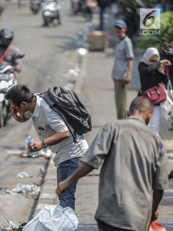 Seorang pria mencuci muka dengan air untuk menghindari sisa gas air mata pasca bentrok massa dengan aparat di Palmerah, Jakarta, Kamis (26/9/2019). Banyak masyarakat yang melintas dan warga sekitar perih pada mata hingga bersin akibat sisa gas air mata. (Liputan6.com/Faizal Fanani)