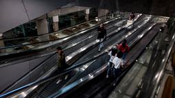 Orang-orang menaiki eskalator di Bandara Suvarnabhumi di Bangkok, saat Thailand melanjutkan skema perjalanan bebas karantina untuk pelancong yang divaksinasi, Selasa (1/2/2022). Program ini sebelumnya ditangguhkan karena melonjaknya kasus Covid-19 di Thailand. (Jack TAYLOR/AFP)