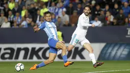 Pemain Real Madrid, Isco (kanan) melepaskan tembakan melewati adangan pemain Malaga, Roberto Jose Rosales pada lanjutan La Liga Santander di Rosaleda stadium, Malaga, (15/4/2018). Madrid menang 2-1. (AP/Miguel Morenatti)