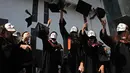 Wisudawan bertopeng Guy Fawkes melemparkan topi wisuda setelah upacara kelulusan mereka di Chinese University of Hong Kong, Hong Kong, Kamis (7/11/2019). Sekitar seribu mahasiswa mengabaikan larangan mengenakan topeng yang dikeluarkan pemerintah pada Oktober 2019. (AP/Kin Cheung)