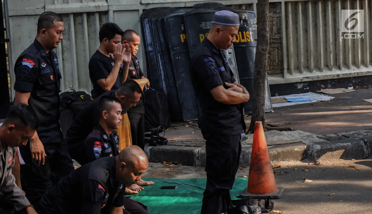 Pasukan Brimob menunaikan ibadah salat Ashar berjamaah disela pengamanan di kawasan Bundaran HI, Jakarta, Rabu (29/5/2019). Di tengah tugas mengamankan situasi, para anggota Brimob tak lupa untuk tetap menjalankan kewajibannya sebagai umat beragama. (Liputan6.com/Faizal Fanani)
