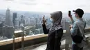 Turis dengan mengenakan masker mengambil gambar dari dek obseravsi di Menara Kuala Lumpur di Kuala Lumpur, Rabu (1/7/2020). Malaysia memasuki pelonggaran Perintah Kontrol Gerakan (MCO) setelah tiga bulan pembatasan karena virus corona Covid-19. (AP Photo/Vincent Thian)