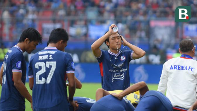 Gelandang Arema, Renshi Yamaguchi membasuh muka dengan air mineral dalam pertandingan melawan Persib Bandung, Minggu (11/9/2022). (Bola.com/Iwan Setiawan)