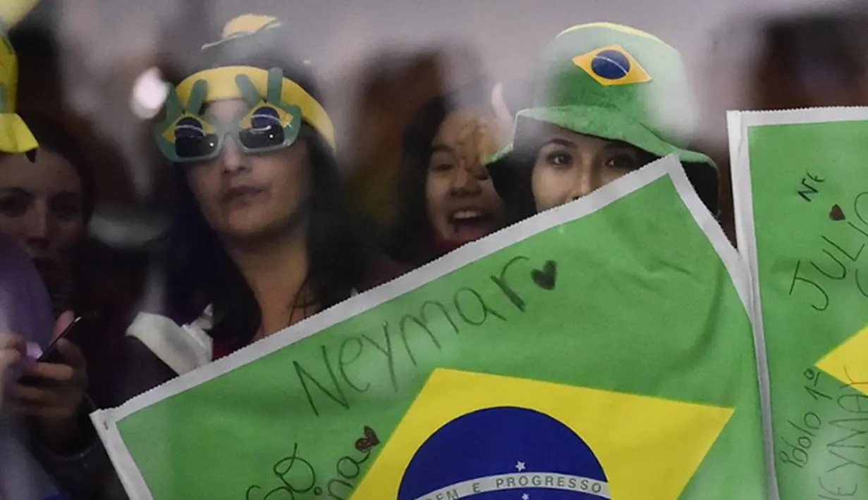 Para wanita menanti munculnya pemain timnas Brasil di Bandara kota Temuco, Cile. (AFP/Rodrigo Buendia)