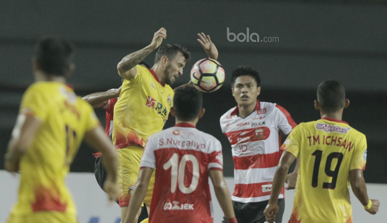 Bek Bhayangkara FC, Paulo Sergio, duel udara dengan pemain Madura United pada laga lanjutan liga 1 di Stadion Patriot, Bekasi, kamis (13/7/2017). Bhayangkara FC menang 2-1 atas Madura United. (Bola.com/M Iqbal Ichsan)