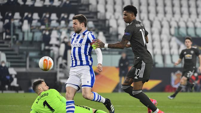 Kiper Real Sociedad Alex Remiro dan Marcus Rashford dari MU memperebutkan bola selama laga babak 32 besar Liga Europa di Allianz Stadium di Turin, Italia, Kamis, 18 Februari 2021. (Marco Alpozzi / LaPresse via AP)