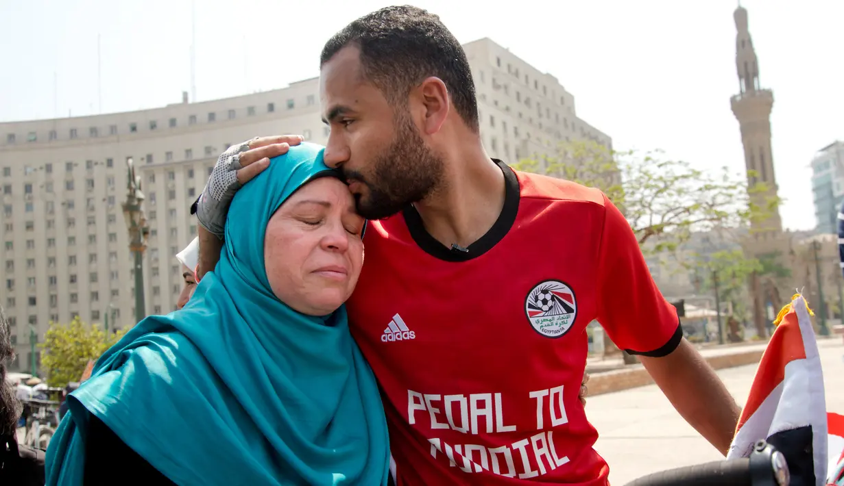Pria asal Mesir, Mohammed Nufal (24) memeluk ibunya sebelum memulai perjalanan menuju Rusia menggunakan sepeda dari Tahrir Square di Kairo, Sabtu (7/4). Nufal nantinya akan mencapai Rusia melintasi tujuh negara di tiga benua selama 65 hari. (AP/Amr Nabil)