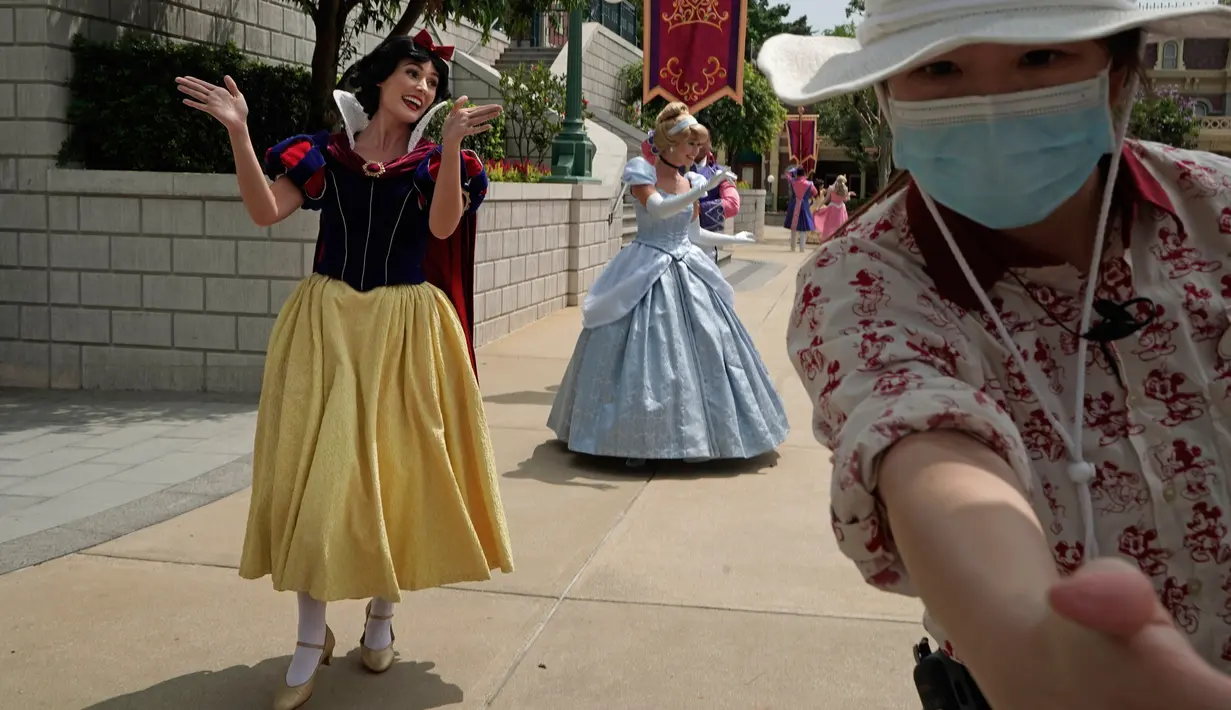 Seorang karyawan menjauhkan pengunjung dari artis di Disneyland Hong Kong pada Jumat (25/9/2020). Setelah dibuka dan tutup kembali, Disneyland Hong Kong dibuka kembali untuk wisatawan.  (AP Photo/Kin Cheung)