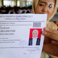 Peserta menunjukkan kartu ujian CPNS Kementerian Kelautan dan Perikanan (KKP) di Jakarta, Minggu (8/10). Pembukaan lowongan CPNS ini dalam rangka mengisi kekosongan 41 jabatan pada Kantor Pusat dan UPT di KKP. (Liputan6.com/Johan Tallo)