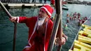 Seorang peserta dalam kostum Sinterklas keluar drai air setelah kompetisi renang 'Copa Nadal' di Port Vell, Barcelona, Rabu (25/12/2019). Lebih dari 300 peserta menempuh jarak sejauh 200 meter pada tradisi lama yang digelar  saat hari Natal tersebut. (Josep LAGO / AFP)