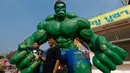 Seorang pria dan cucunya berpose dengan patung tokoh komik "Hulk" di kuil Tamru di provinsi Samut Prakan, Thailand, (3/3). Pihak Candi mengatakan telah menyiapkan patung-patung karakter komik Marvel untuk menarik pengunjung. (REUTERS/Chaiwat Subprasom)