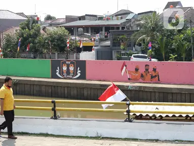 Warga berjalan di depan mural bertema Kemerdekaan RI pada dinding turap Sungai Ciliwung di kawasan Kampung Melayu, Jakarta, Minggu (16/8/2020). Mural karya petugas Pekerja Penanganan Sarana dan Prasarana Umum (PPSU) itu dibuat dalam rangka memeriahkan HUT ke-75 RI. (Liputan6.com/Immanuel Antonius)