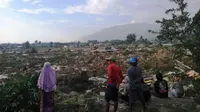 Warga memandangi bangunan yang runtuh akibat gempa Palu. (Twitter @Sutopo_PN)