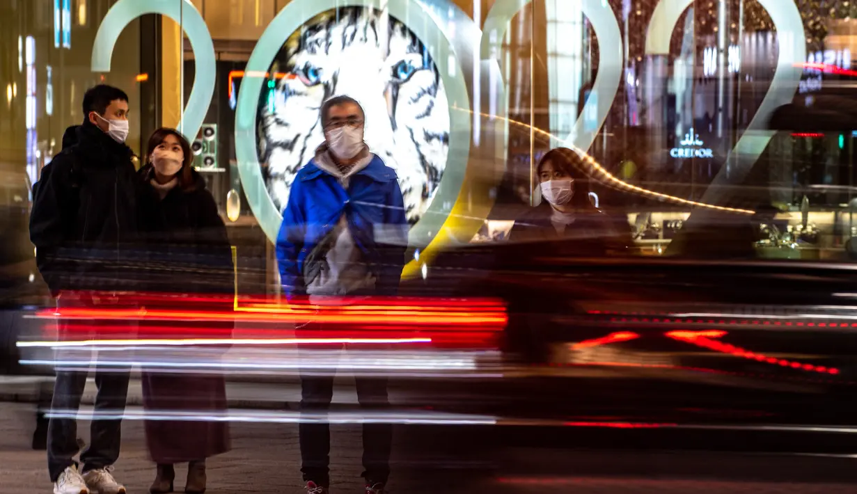 Pejalan kaki menunggu untuk menyeberang jalan di distrik Ginza Tokyo (18/1/2022). Jepang melaporkan rekor tertinggi infeksi Covid-19 baru yang dipicu oleh varian Omicron. (AFP/Philip Fong)
