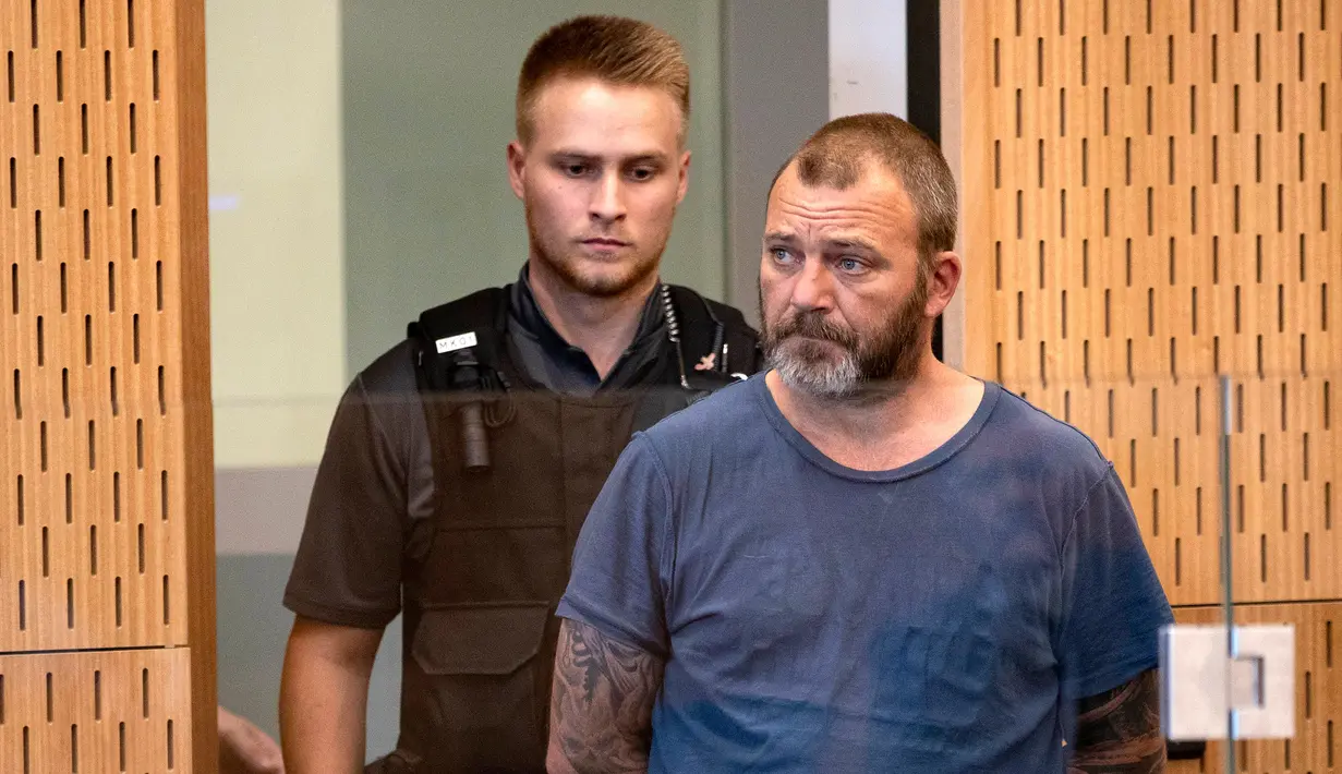 Terduga penyebar video serangan Masjid Al Noor, Philip Arps (kanan) menjalani persidangan di Pengadilan Distrik Christchurch, Selandia Baru, Rabu (20/3). Arps menghadiri dengan pengawalan ketat polisi. (Mark Mitchell/Pool Photo via AP)