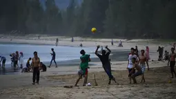 Wisatawan bermain bola saat berlibur Lebaran di Pantai Lhoknga, Aceh Besar, Aceh, Minggu (9/6/2019). (CHAIDEER MAHYUDDIN/AFP)