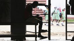 Seorang pria mengobrol di ponselnya di Harare, Zimbabwe, Senin (29/11/2021). Banyak negara memberlakukan larangan penerbangan terhadap negara-negara Afrika selatan karena kekhawatiran atas varian baru (Covid-19) Omicron. (AP/Jerome Delay)