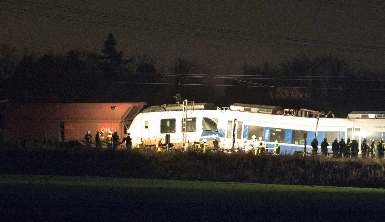 Sejumlah petugas berdiri di samping gerbong yang rusak usai terjadinya tabrakan kereta di Meerbusch, Jerman, (5/12). Akibat musibah tersebut puluhan orang terluka saat kereta penumpang bertabrakan dengan kereta kargo. (Arnulf Stoffel/dpa via AP)