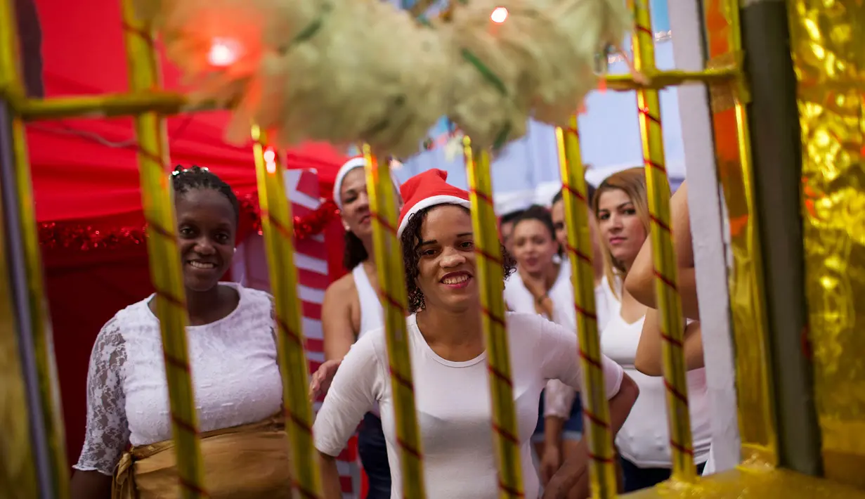 Narapidana wanita tersenyum dari balik sel di Penjara Nelson Hungria, Rio de Janeiro, Brasil, Kamis (13/12). Para narapidana mendekorasi ruangan mereka dengan hiasan untuk menyambut Natal. (AP Photo/Silvia Izquierdo)