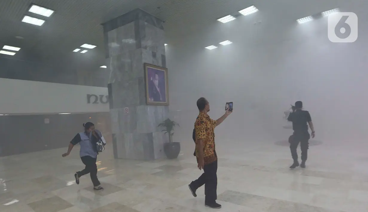Pegawai berhamburan ke luar ruangan saat kepulan asap putih memenuhi Gedung Nusantara III, Kompleks Parlemen, Senayan, Jakarta, Senin (24/2/2020). Menurut  Sekjen DPR  Indra Iskandar, asap itu bukan dari kebakaran melainkan kerusakan sistem aerosol pada pukul 12.00 WIB. (Liputan6.com/Johan Tallo)