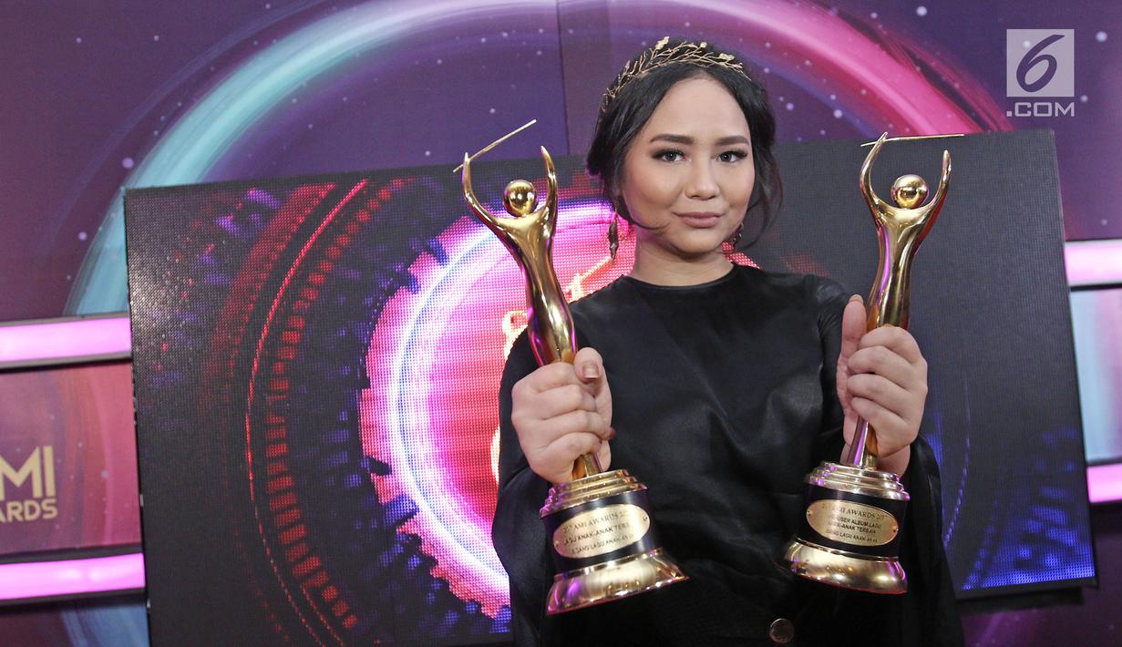 Penyanyi Gita Gutawa berpose memenggang piala usai meraih penghargaan Anugerah Musik Indonesia (AMI) Awards 2017 di Teater Garuda TMII, Jakarta, Kamis (16/11). (Liputan6.com/Herman Zakharia)