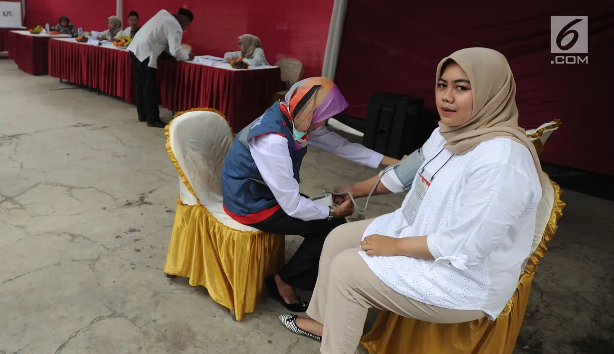 Petugas medis Puskesmas memeriksa tekanan darah petugas Kelompok Penyelenggara Pemungutan Suara (KPPS) yang bertugas saat pemungutan suara ulang di TPS 49 Rengas, Ciputat Timur, Tangsel, Rabu (24/4). Pemeriksaan untuk antisipasi menurunnya kesehatan fisik akibat kelelahan. (merdeka.com/Arie Basuki)