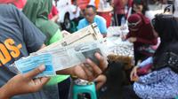 Warga menunjukkan STNK yang baru diperpanjang di gerai Samsat Keliling Car Free Day, Jakarta, Minggu (21/10). Layanan pembayaran pajak Surat Tanda Nomor Kendaraan (STNK) bisa dilakukan tanpa membawa salinan atau BPKB. (Liputan6.com/Angga Yuniar)